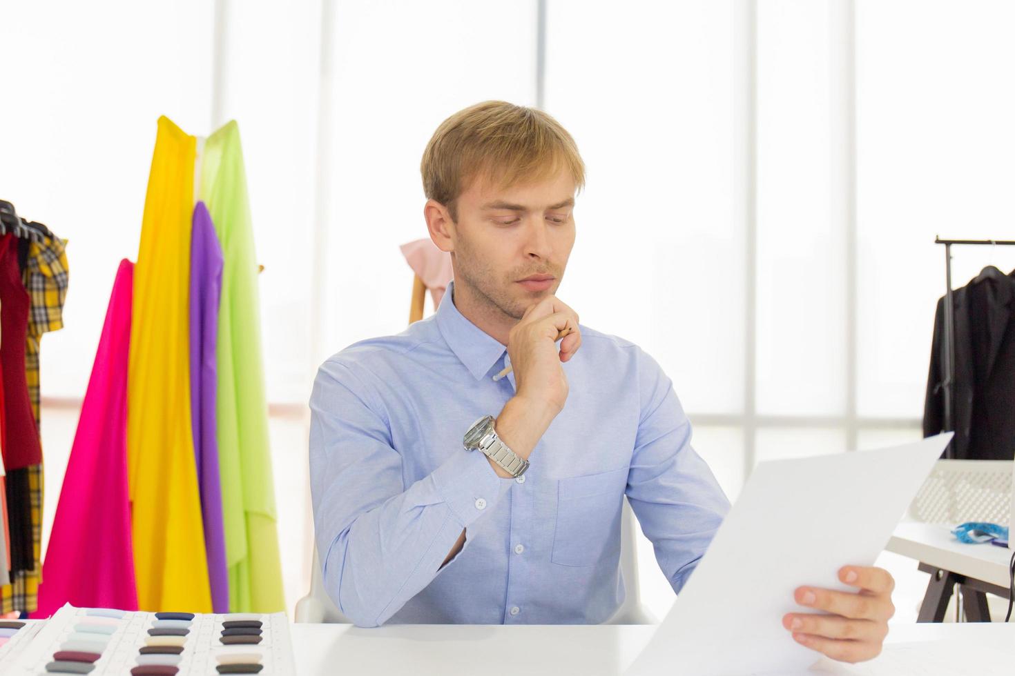 Male designers who are sketching on paper to design clothes photo