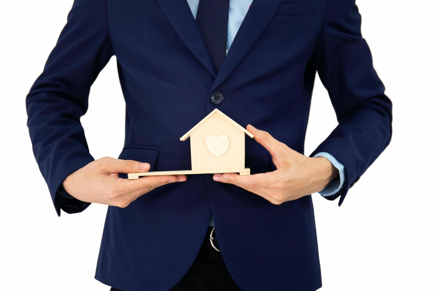 Businessmen stand and hold A small wooden house in his hand and isolated on white background photo