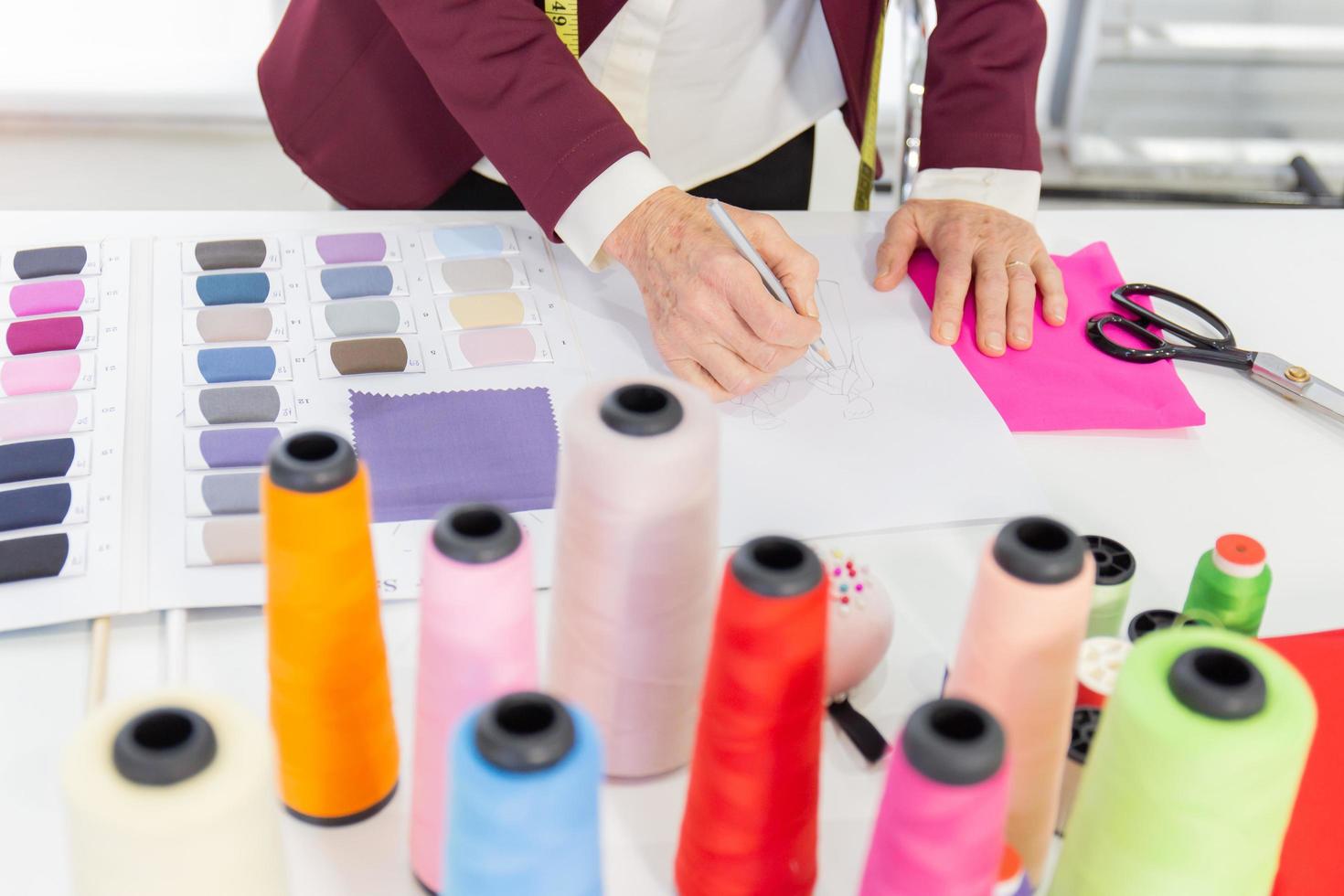 Elderly female designers sketching on paper to design clothes photo