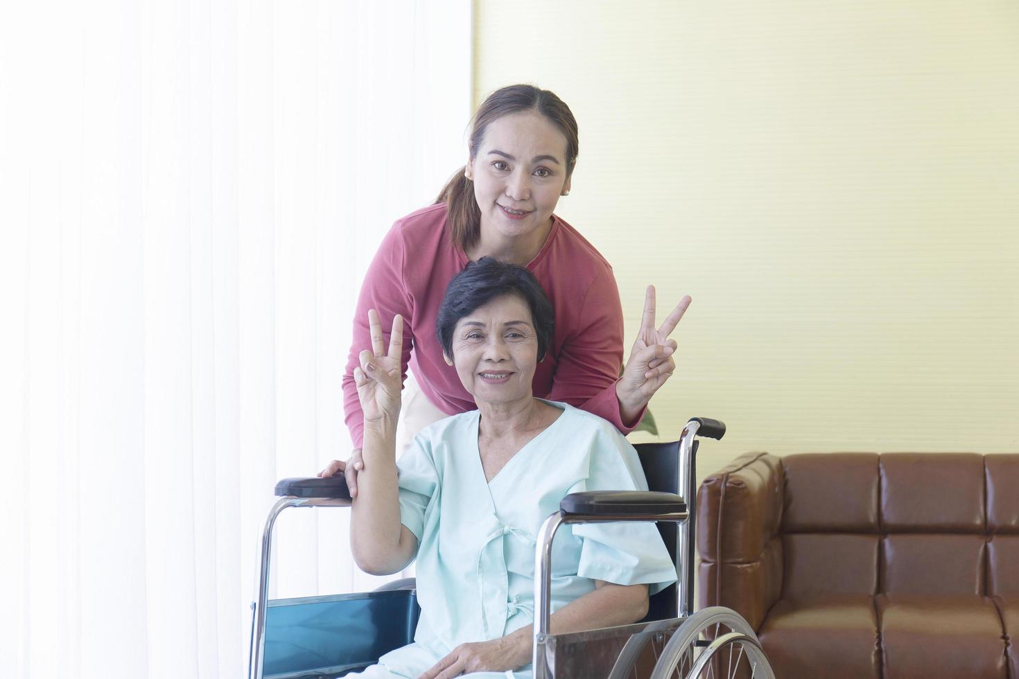 The Asian family raised two fingers, the sick mother, sitting in a wheelchair, treated in a hospital, and had a daughter to take care of closely. photo