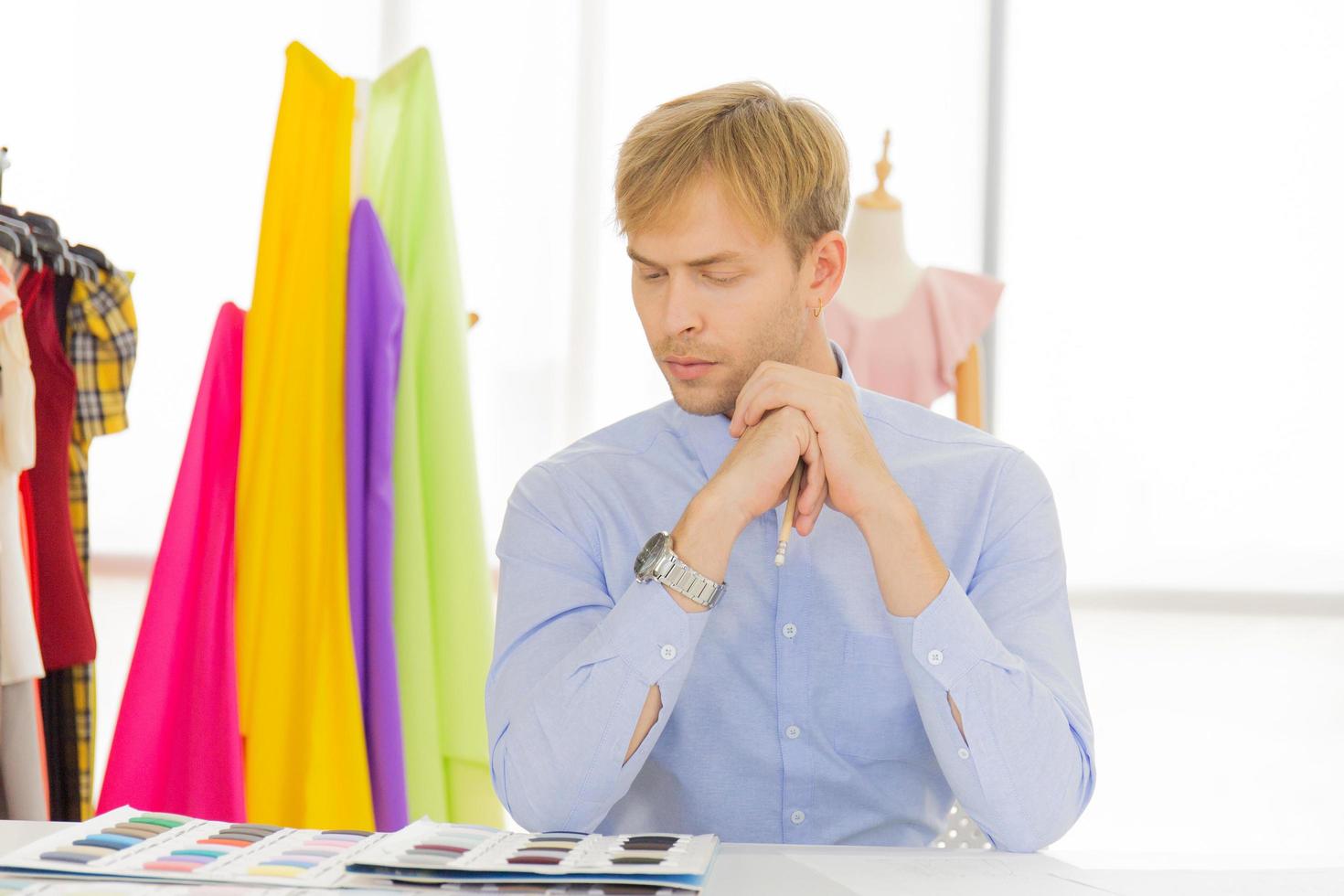 los diseñadores de costura masculinos profesionales en la oficina tienen una variedad de combinaciones de colores de tela. foto