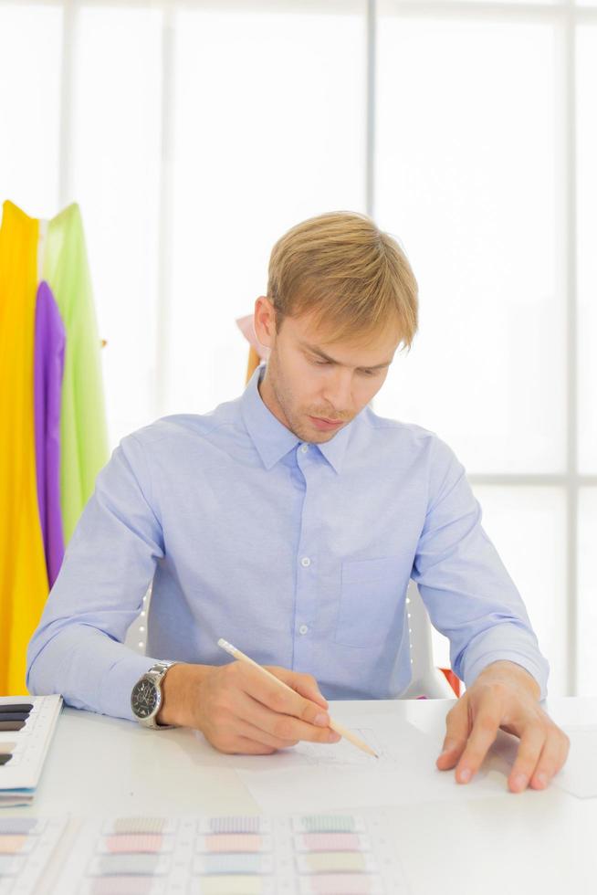 Male designers who are sketching on paper to design clothes photo