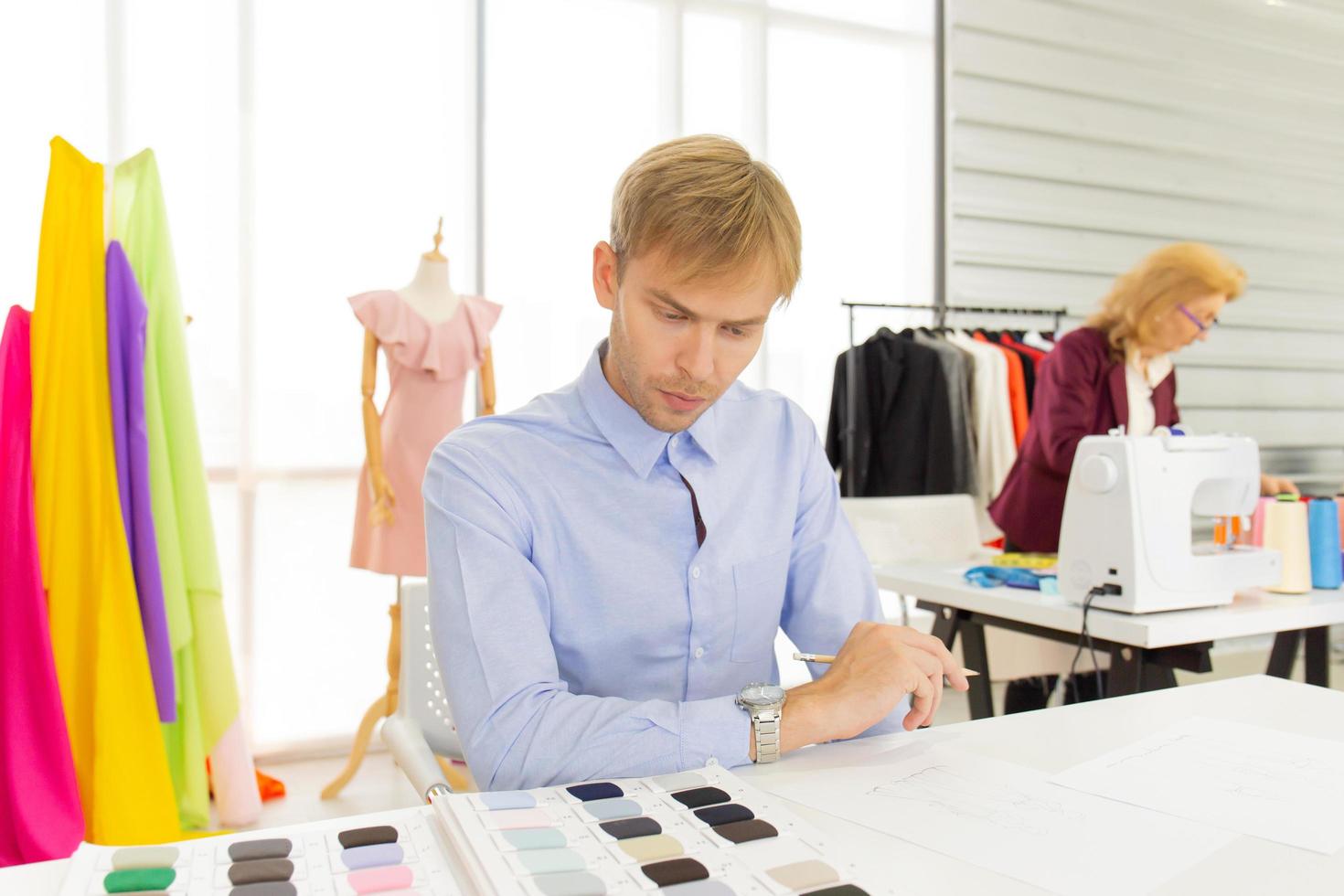 Male designers who are sketching on paper to design clothes photo