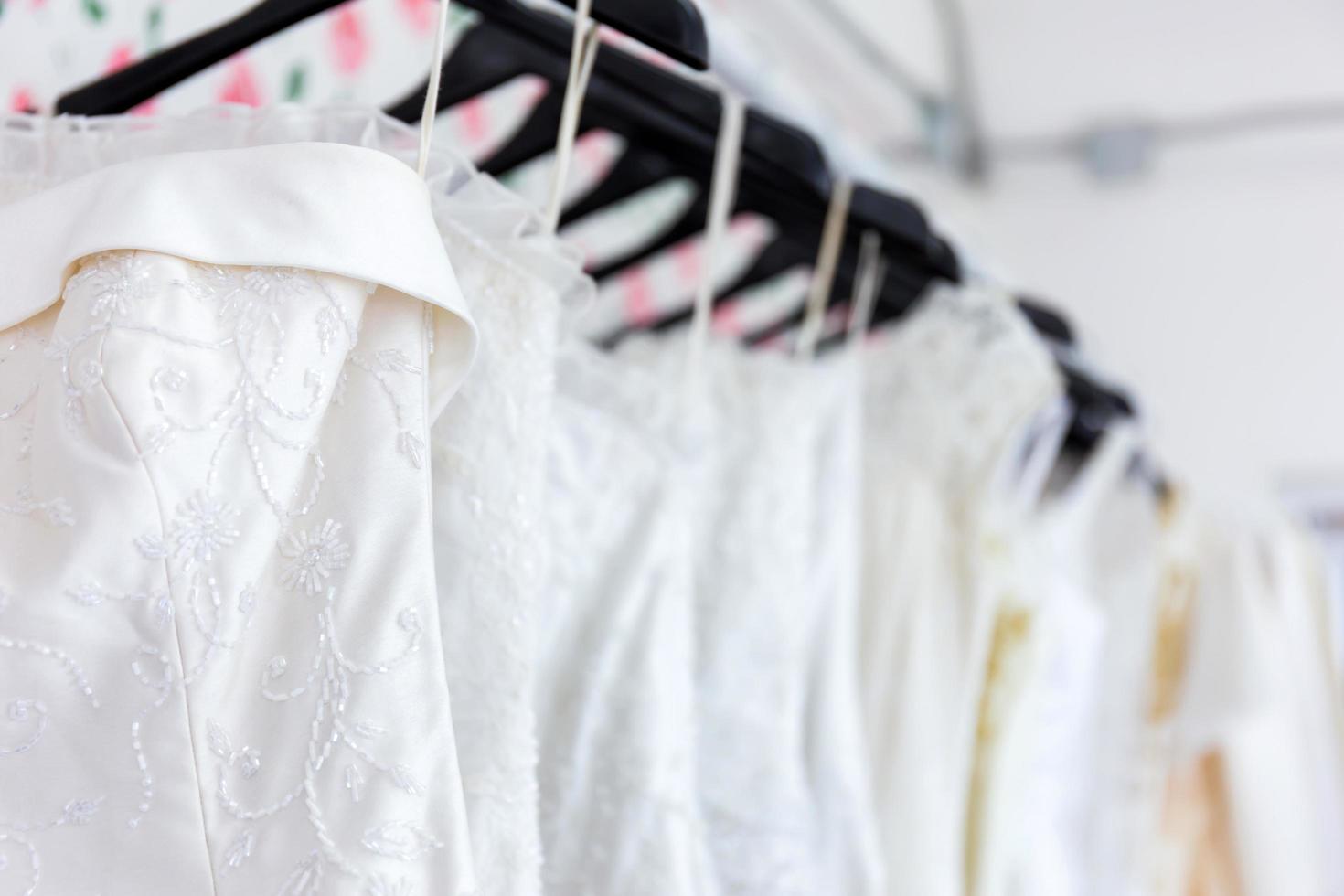 hay una gran variedad de vestidos de novia que cuelgan en el tendedero. foto