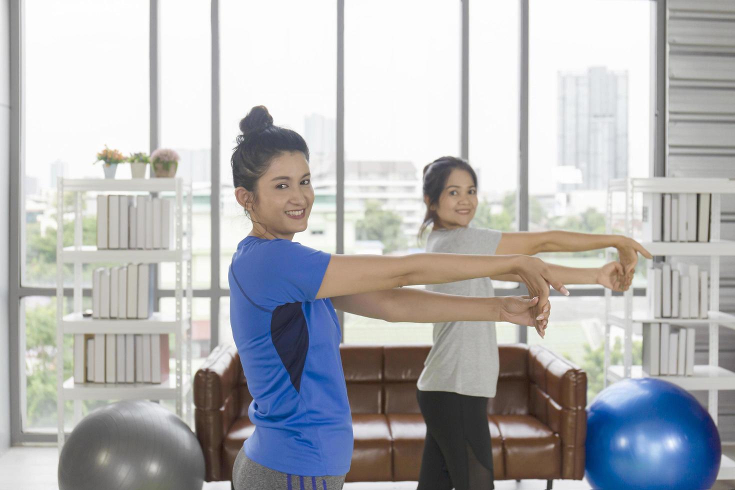 Two middle-aged Asian women are doing yoga inside their home. photo