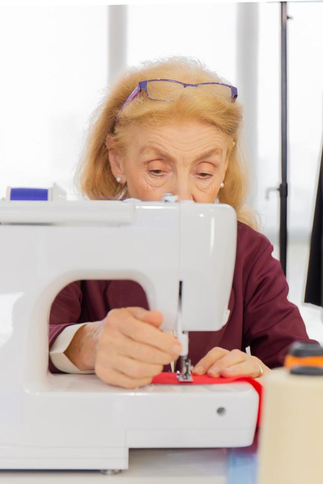 Professional female designers are sewing with small sewing machines on the table. photo