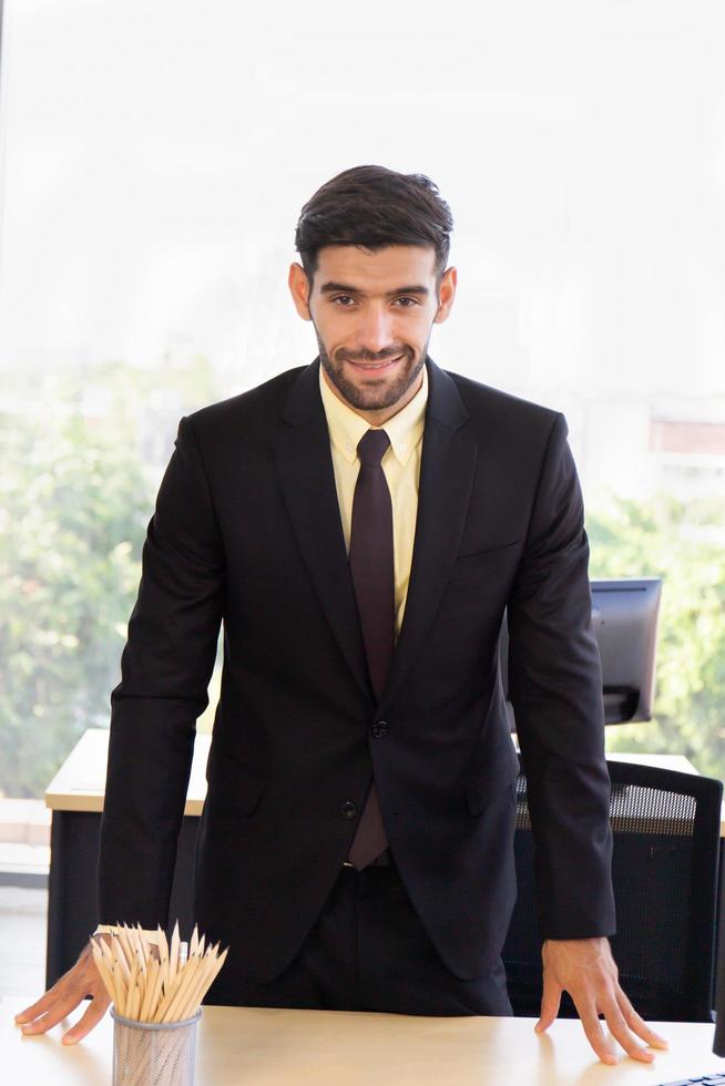 un hombre de negocios con un traje bien vestido parado en la oficina con una sonrisa brillante foto