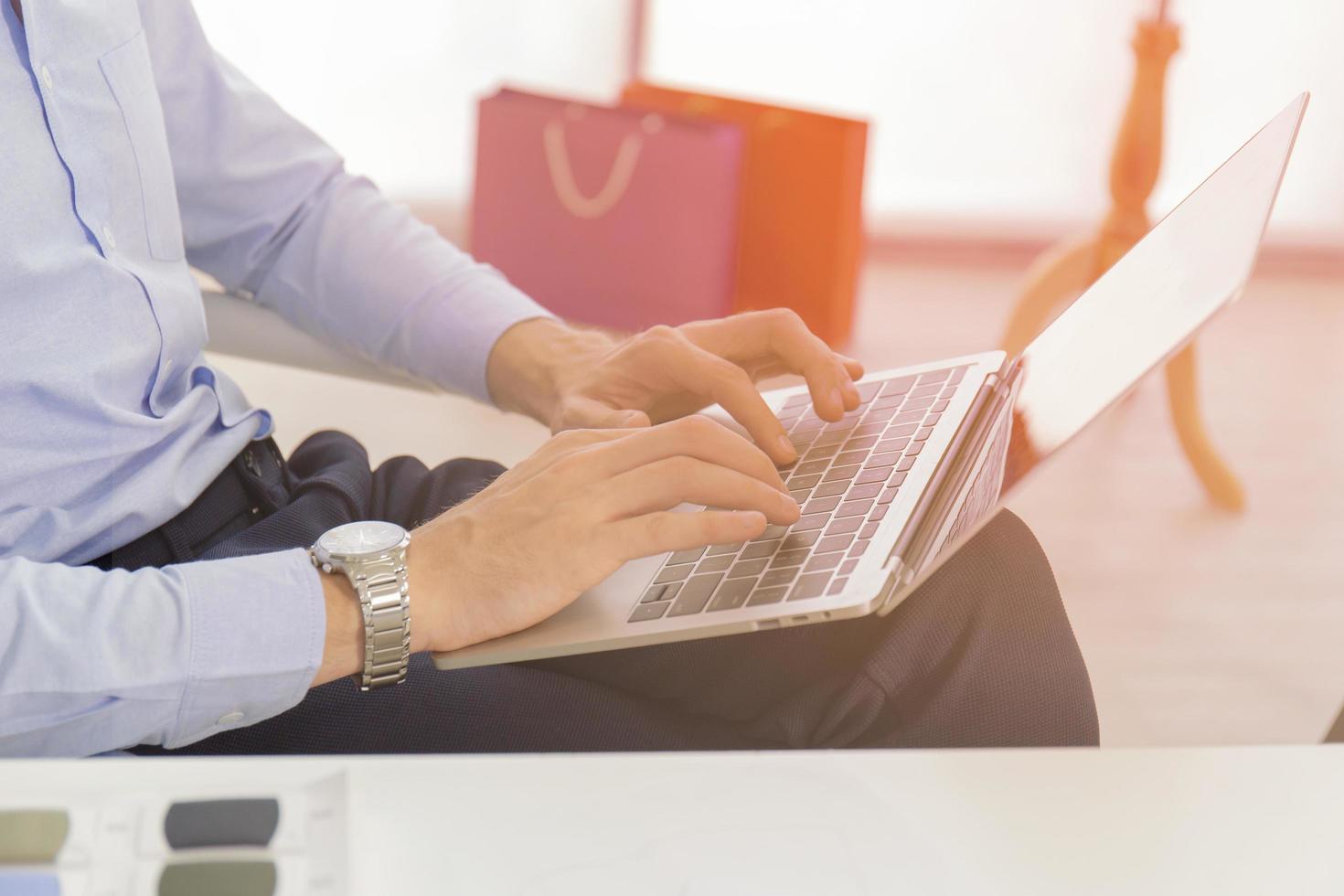 A businessman with a close up in a blue shirt, keyboard, text on a modern notebook computer at a desk in the house Men work online via banks on netbooks, laptops. Office workspace with netbook photo