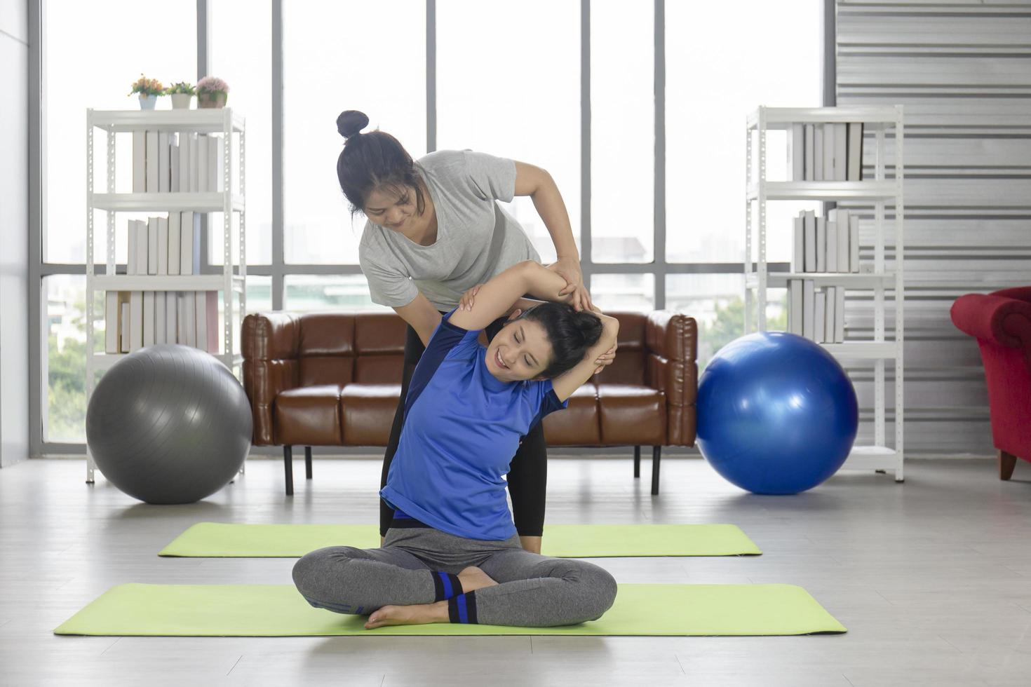 2 middle-aged Asian women doing yoga on a rubber mat in her home. photo