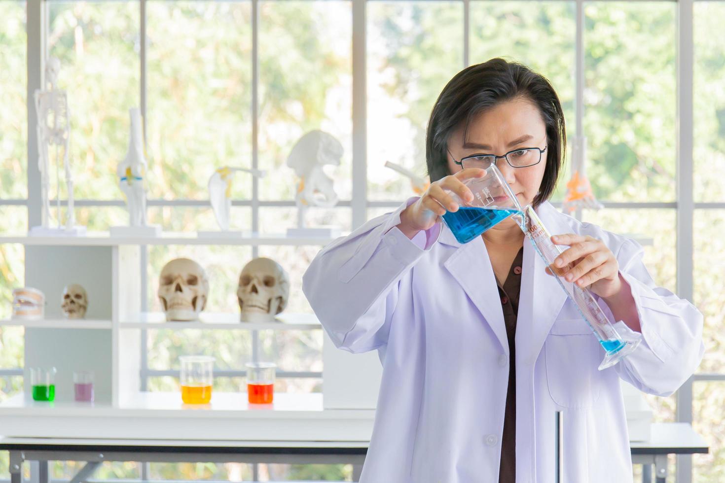 Discovering a cure for an Asian female scientist who is concentrated, holding a test tube and watching while working. photo