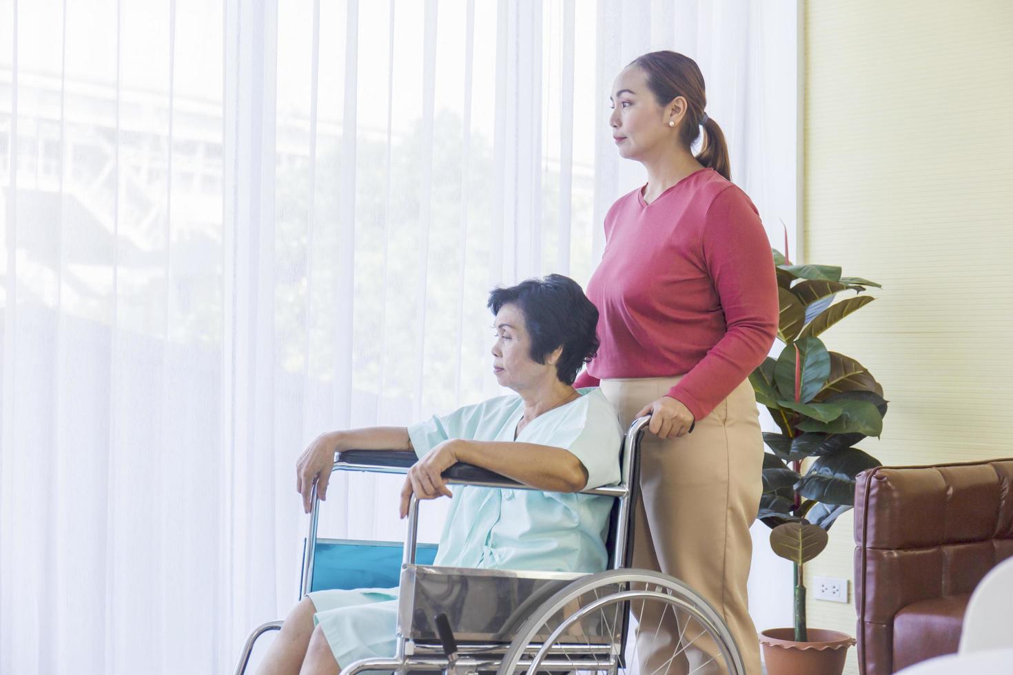 The elderly Asian woman in a wheelchair has her daughter to take care. photo