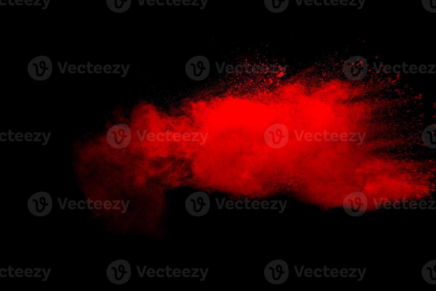 Abstract red dust explosion on black background. Freeze motion of red powder splash. photo