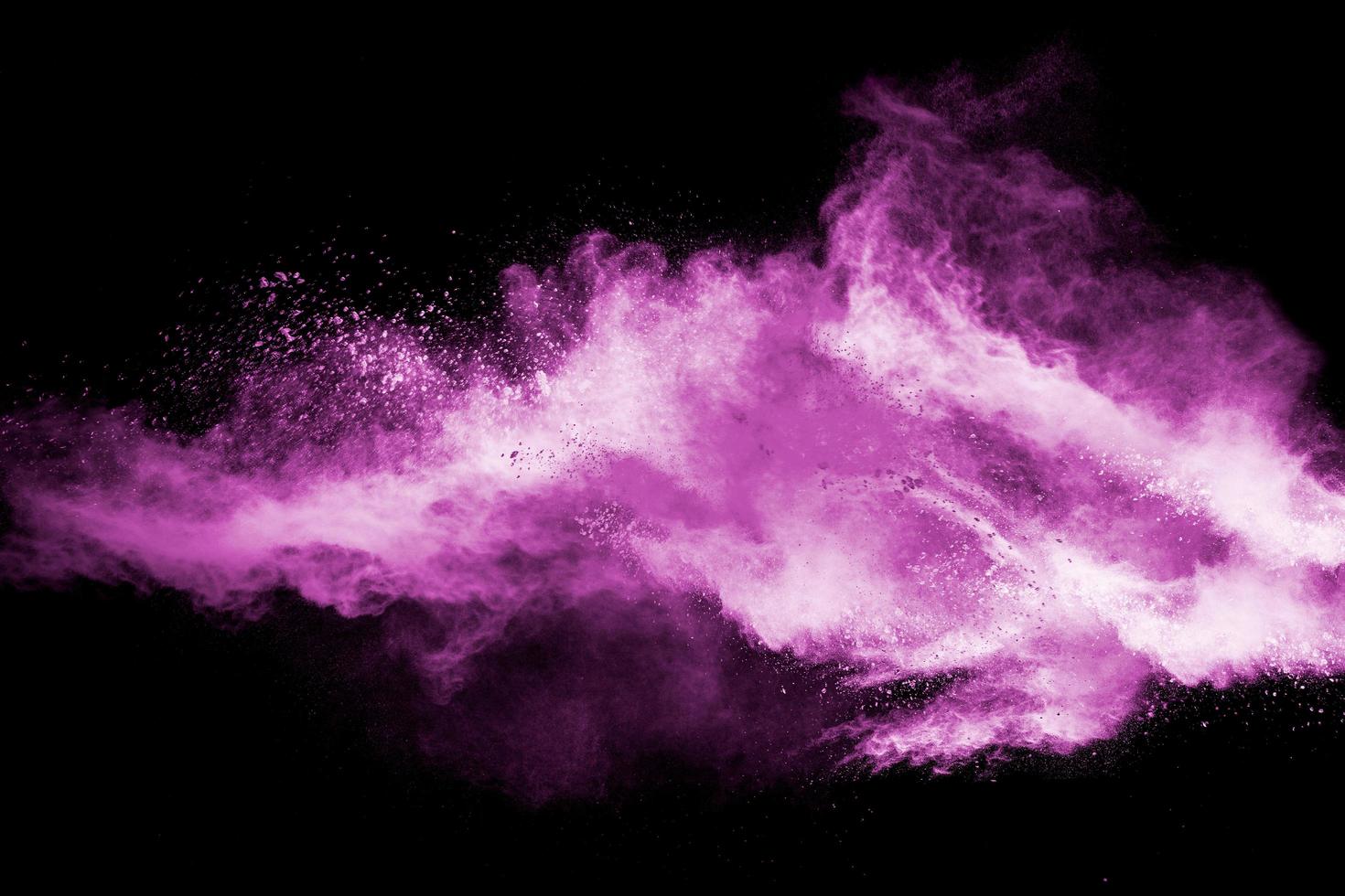 Abstract pink dust particles explosion on black background.Freeze motion of pink powder splash. photo