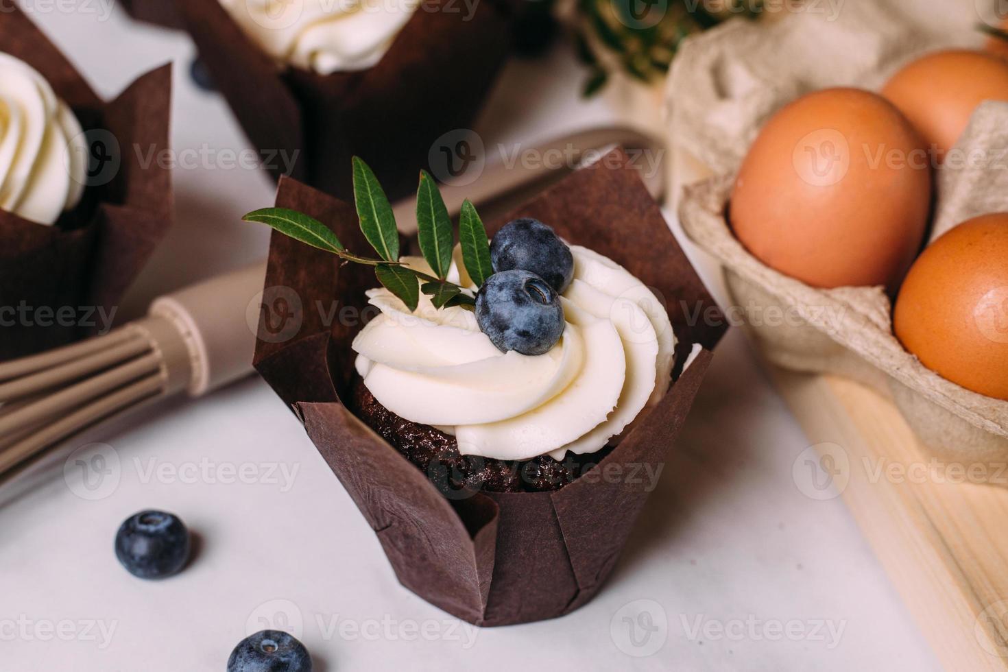 cupcakes with cream and blueberries on kitchen table photo