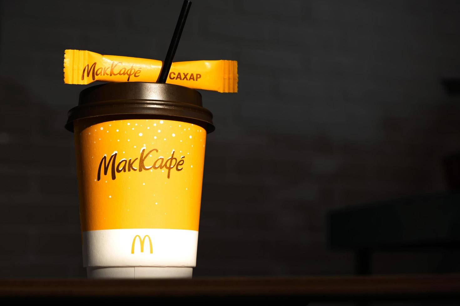 Coffee to go of McDonald's with the inscription Maccafe in Russian stick with sugar on the table with a napkin and a straw. Fast food restaurant chains. Russia, Kaluga, March 21, 2022. photo