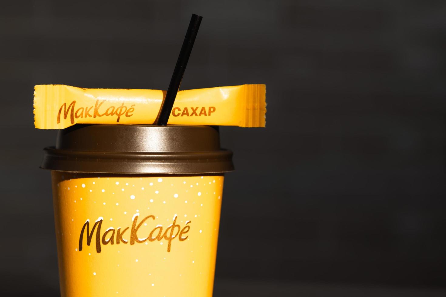 Coffee to go of McDonald's with the inscription Maccafe in Russian stick with sugar on the table with a napkin and a straw. Fast food restaurant chains. Russia, Kaluga, March 21, 2022. photo