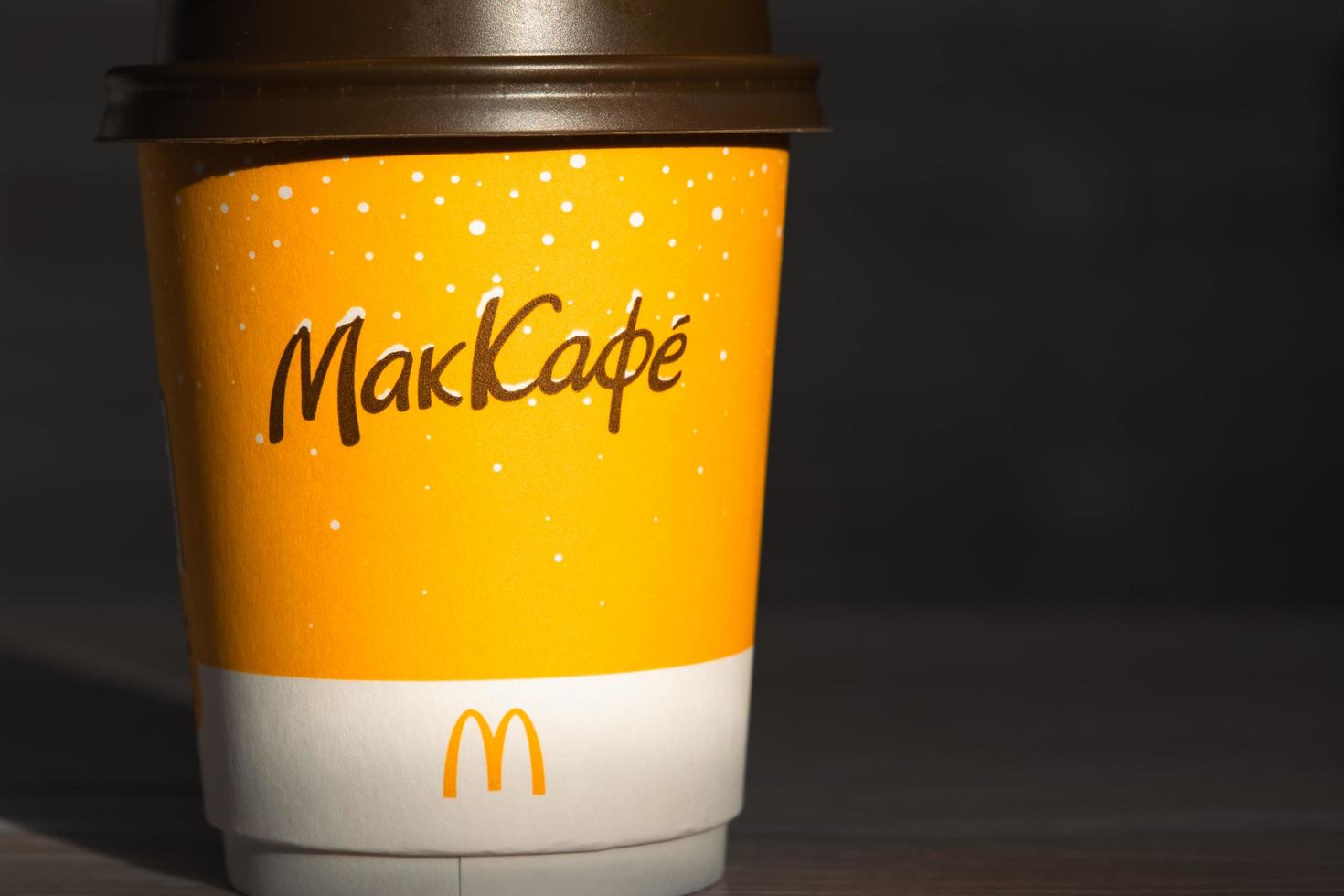 Coffee to go of McDonald's with the inscription Maccafe in Russian stick with sugar on the table with a napkin and a straw. Fast food restaurant chains. Russia, Kaluga, March 21, 2022. photo