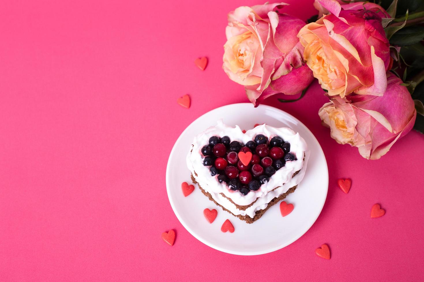 Heart shaped cake decorated with red currant on pink back photo