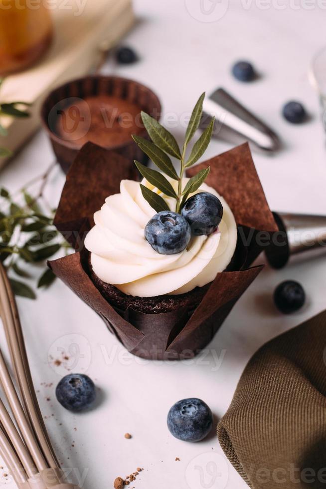 cupcakes with cream and blueberries on kitchen table photo