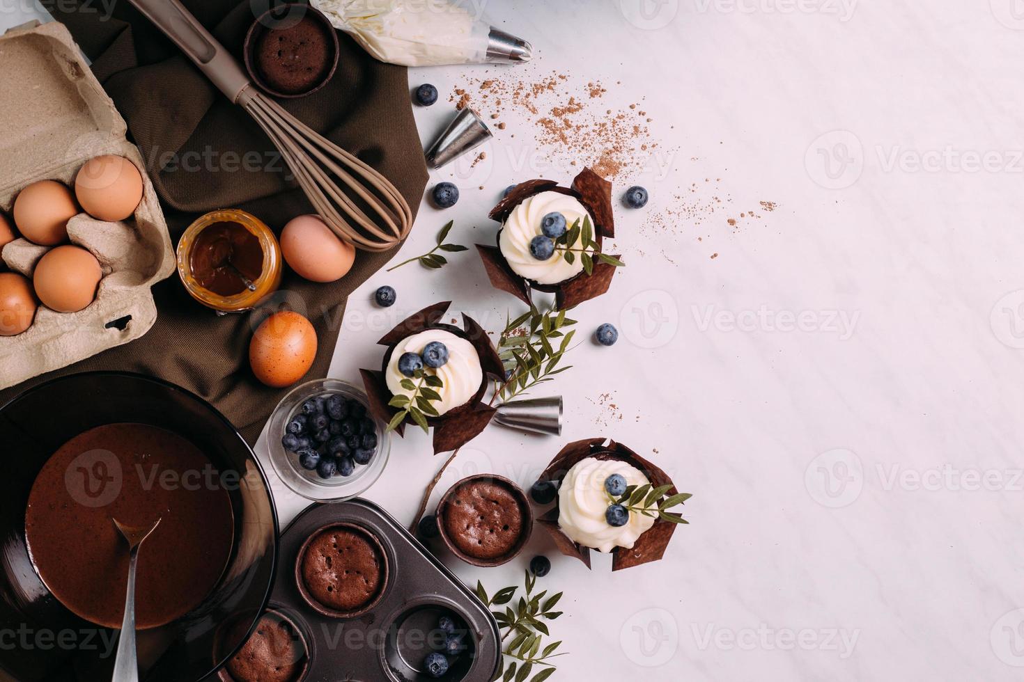 cupcakes with cream and blueberries on kitchen table photo