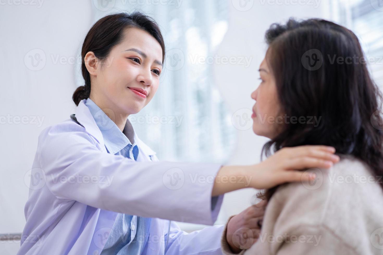 Asian female doctor examining an elderly woman at home photo