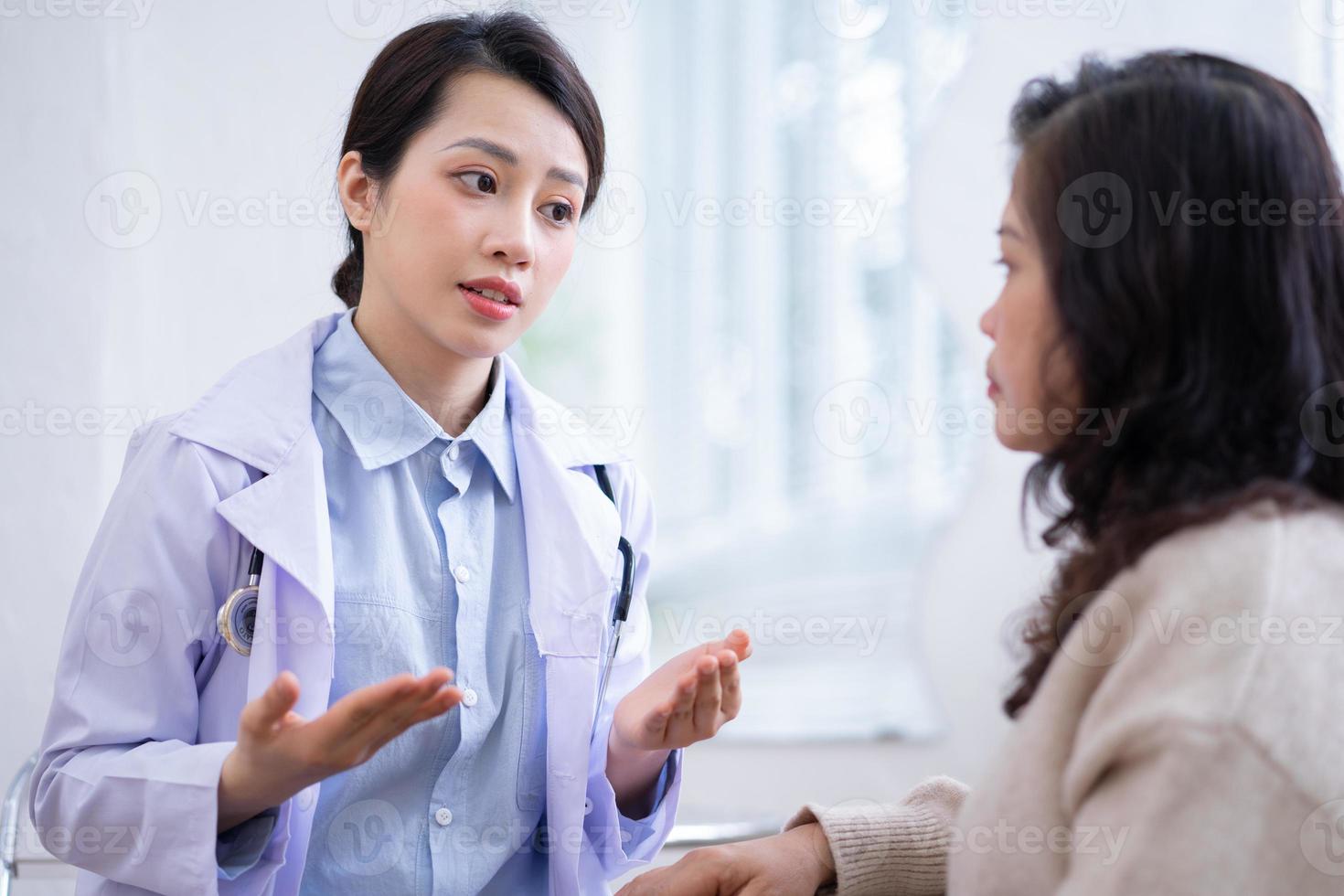 Asian female doctor examining an elderly woman at home photo