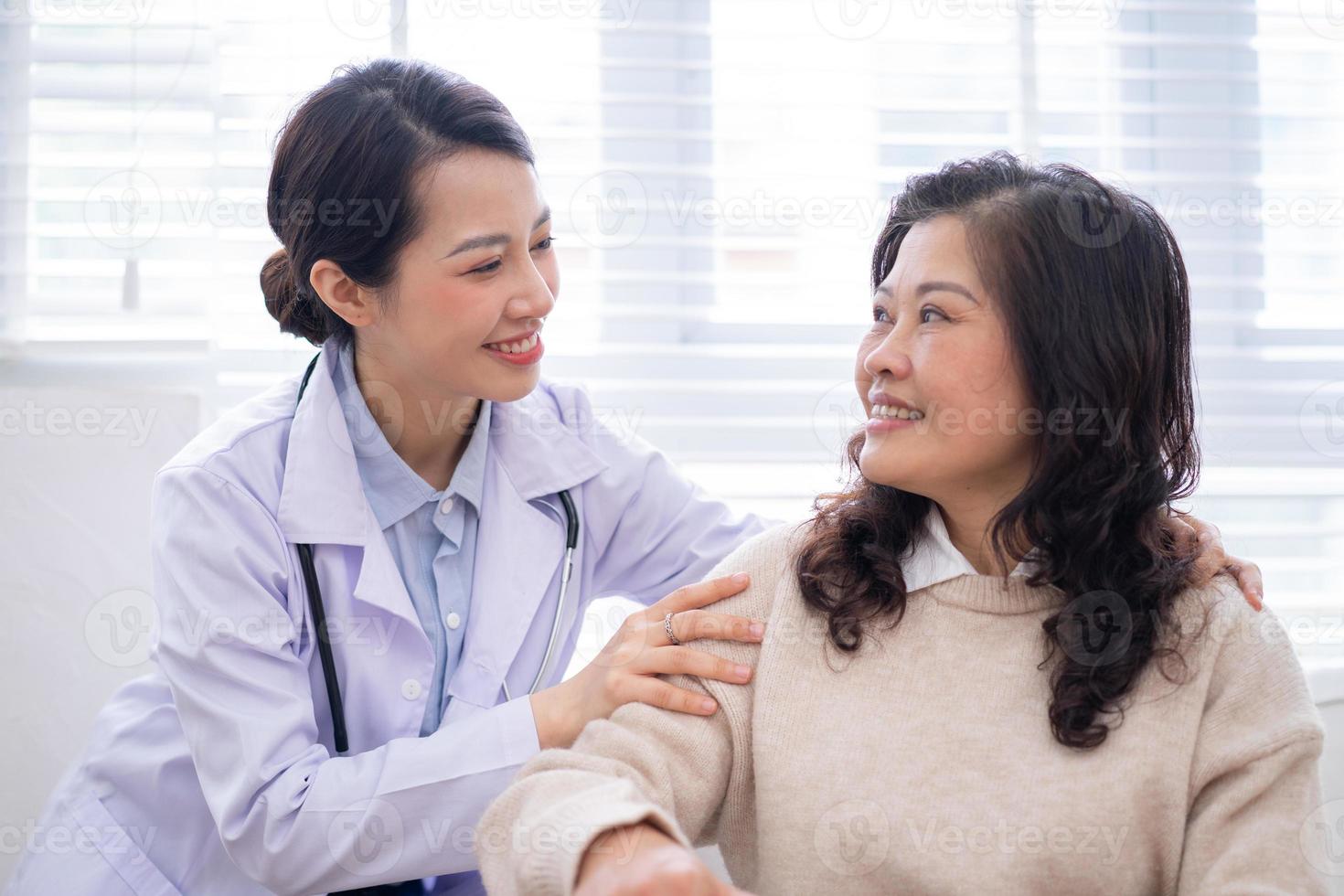 Asian female doctor examining an elderly woman at home photo