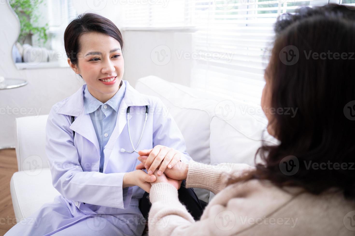 Asian female doctor examining an elderly woman at home photo