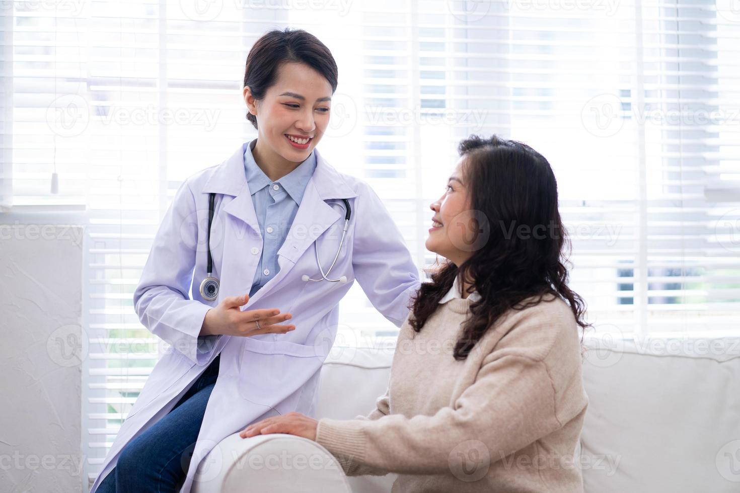 Asian female doctor examining an elderly woman at home photo