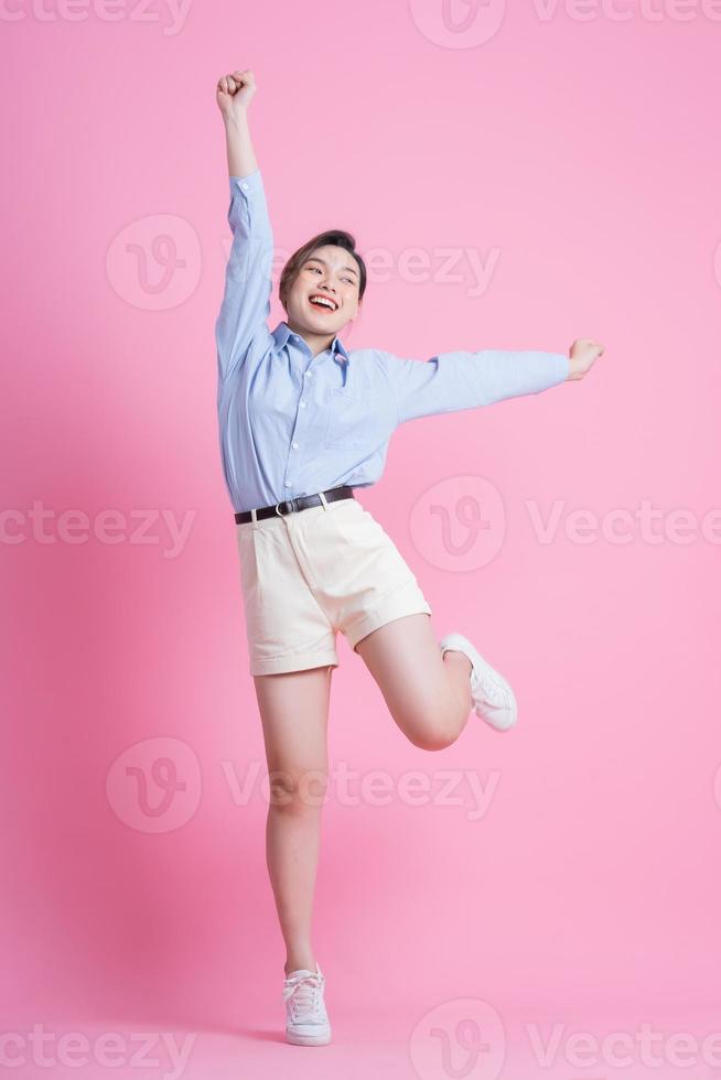 Full length image of young Asian woman posing on pink background photo