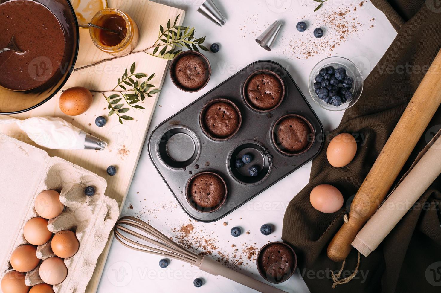 cupcakes with cream and blueberries on kitchen table photo