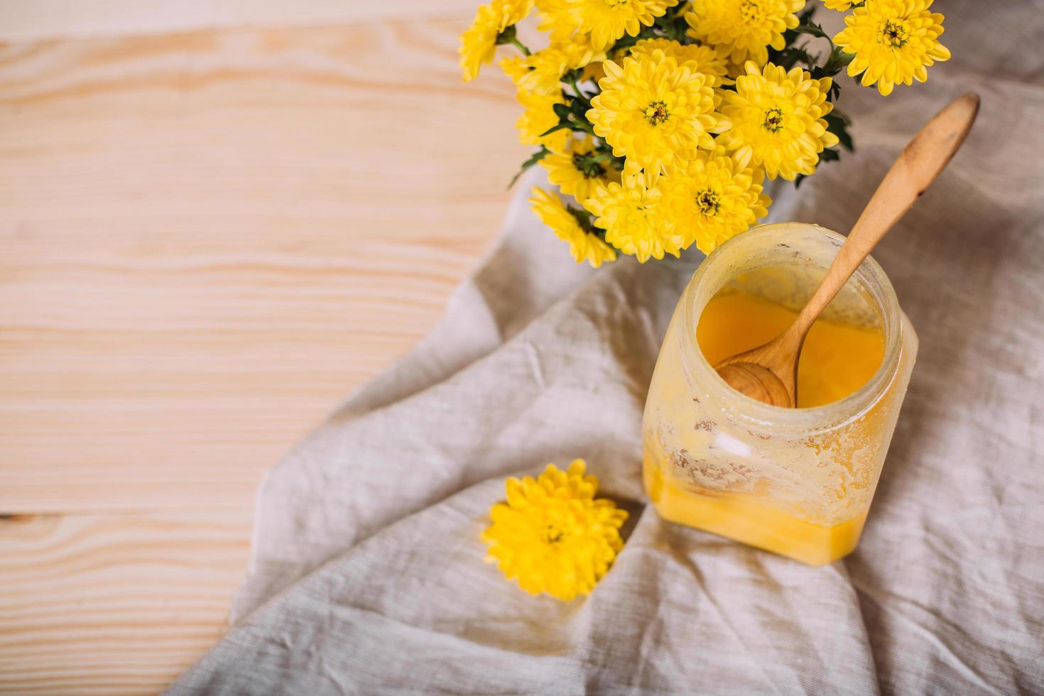 A jar of solid honey and flowers on wooden background. photo