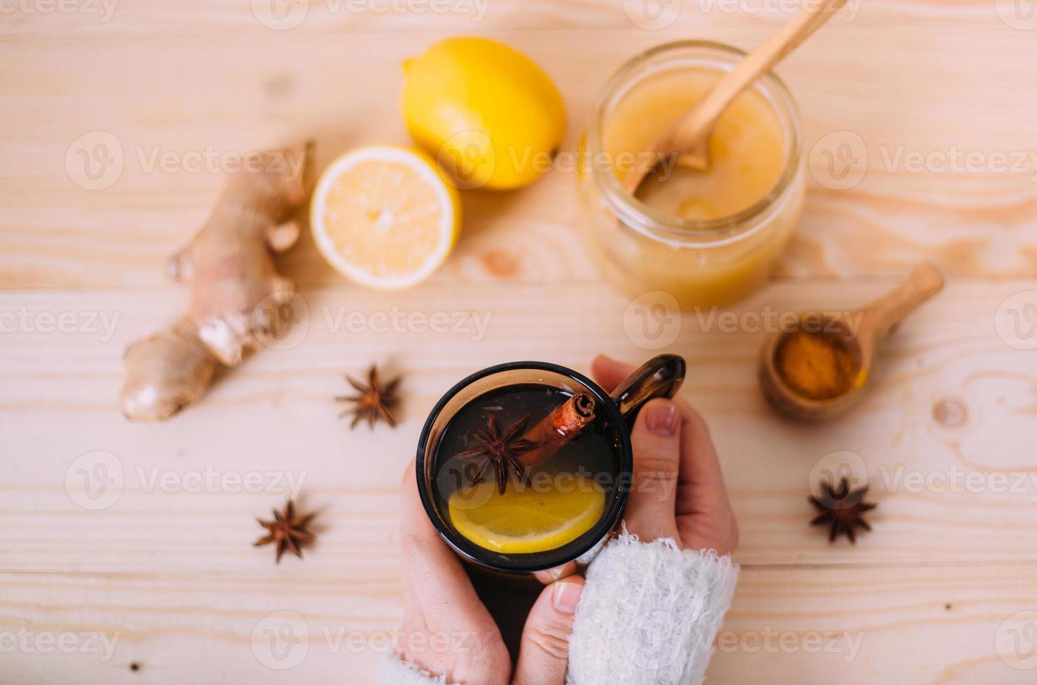 Close up of female hands holding cup of warm water with lemon photo
