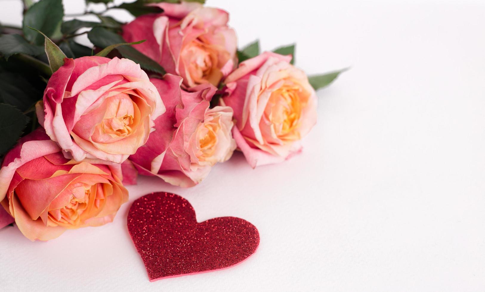 Pink roses and heart shape ornaments on white background photo