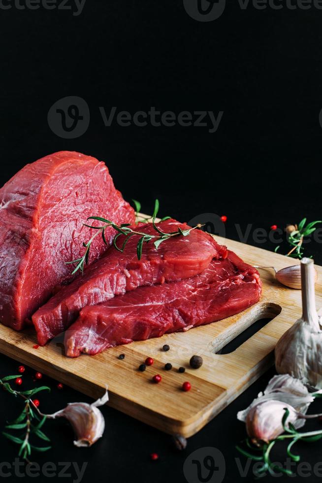 Fresh and raw meat. Whole piece of red beef ready to cook on the grill or BBQ . Background black blackboard. photo