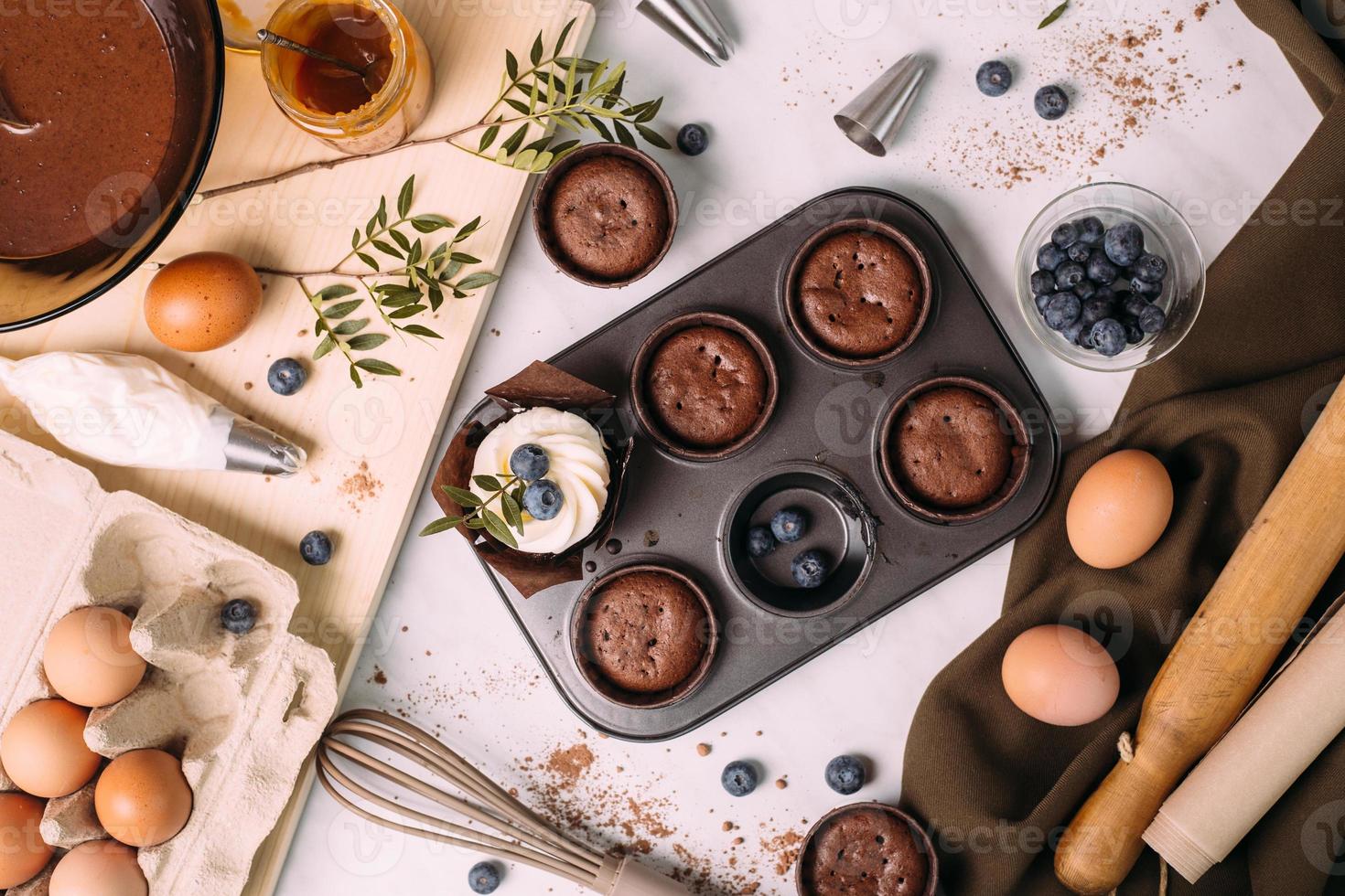 cupcakes with cream and blueberries on kitchen table photo