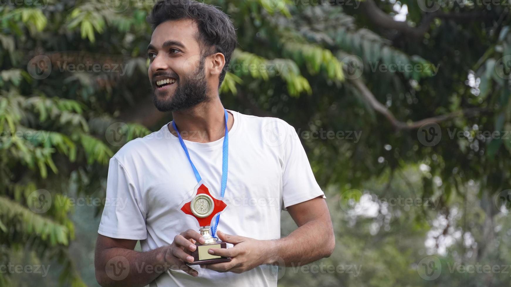 indian smart Collage, school boy holding gold medal and trophy cup photo
