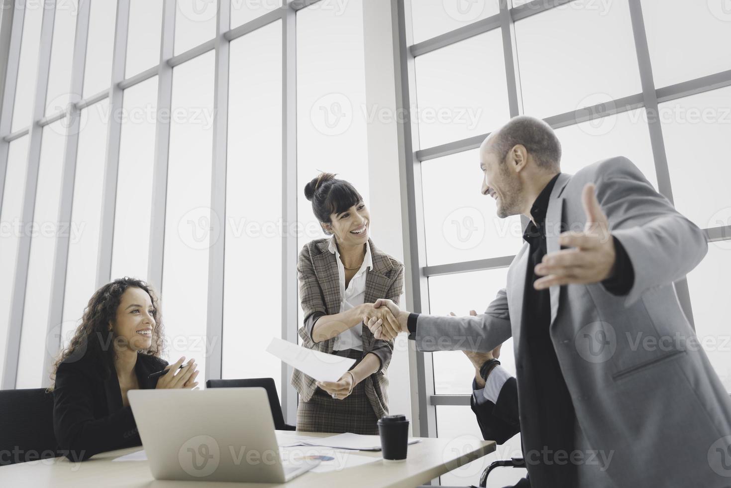 Smiling businesswoman handshake celebrate success or acheivement with team photo