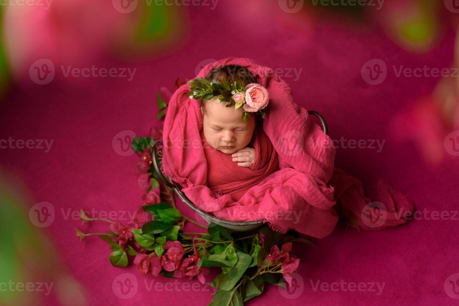 Closeup portrait of cute newborn girl sleeping wrapped in purple soft blanket, wearing stylish head flower, baby fashion concept photo