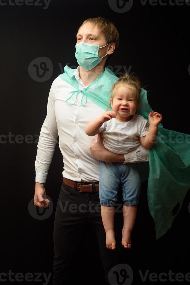 father in a medical mask holds his little daughter. The concept of protecting children during the epidemic of coronavirus photo