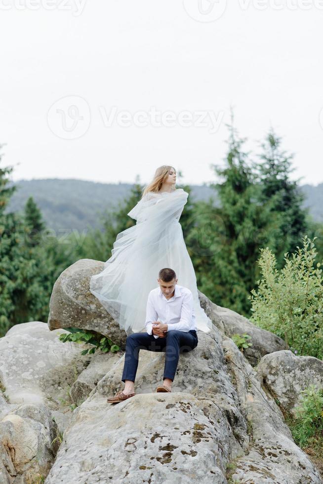 sesión de fotos de una pareja enamorada en las montañas. la niña está vestida como una novia con un vestido de novia.