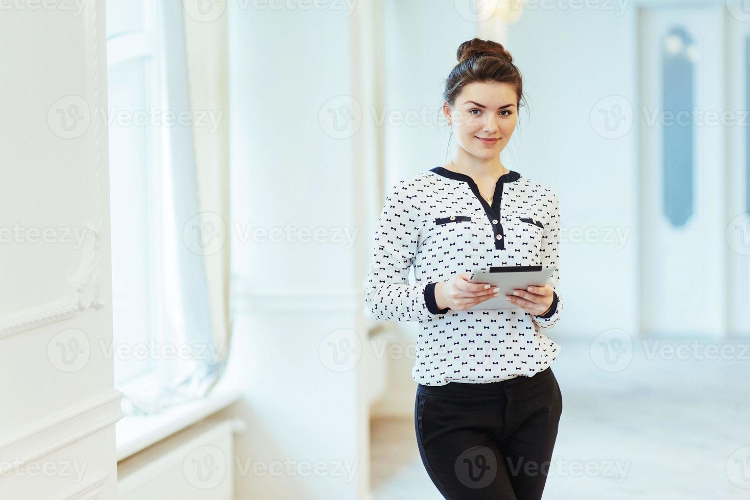 mujer de negocios sonriente sosteniendo una tableta en la oficina foto