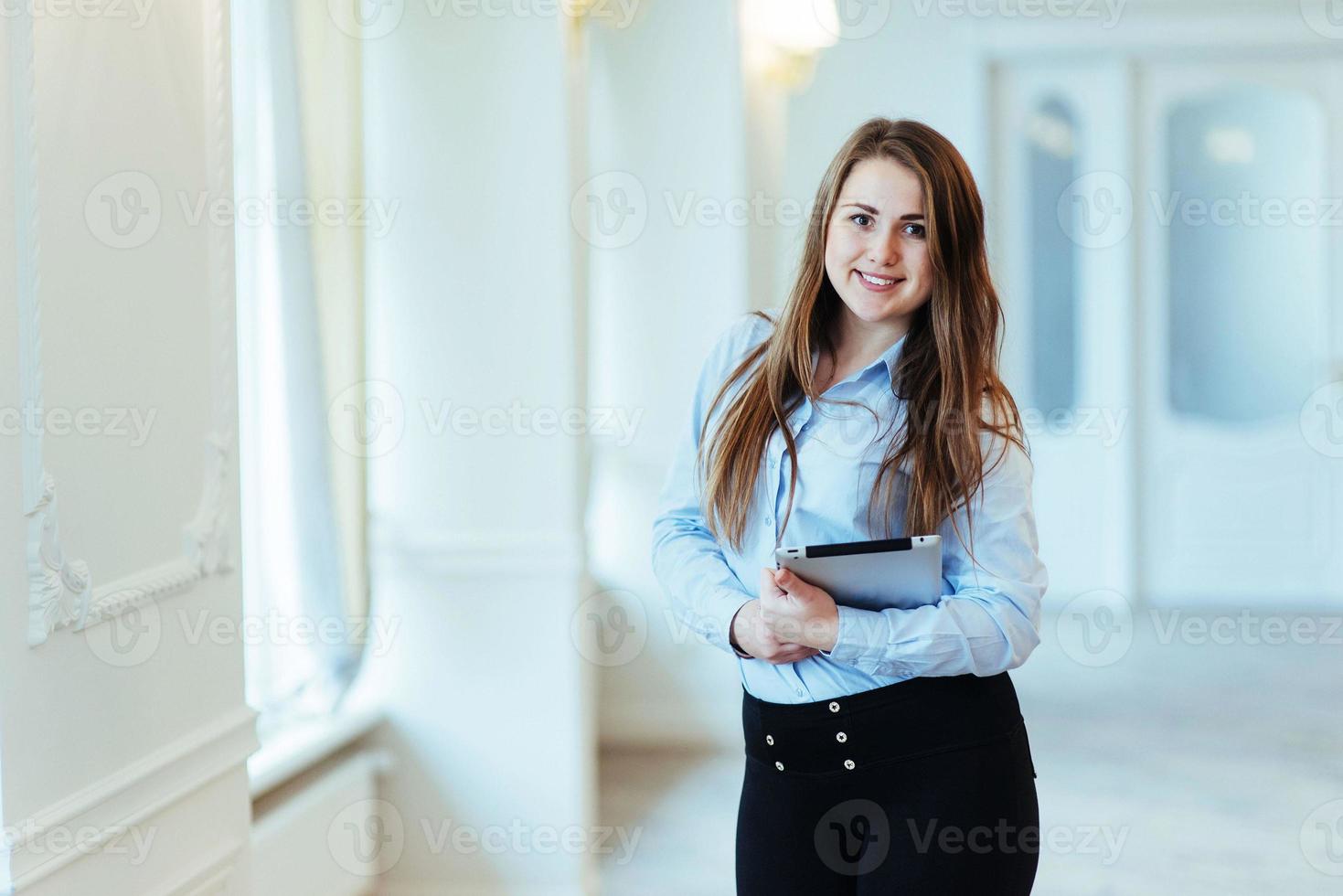 Smiling business woman holding a tablet computer at the office photo