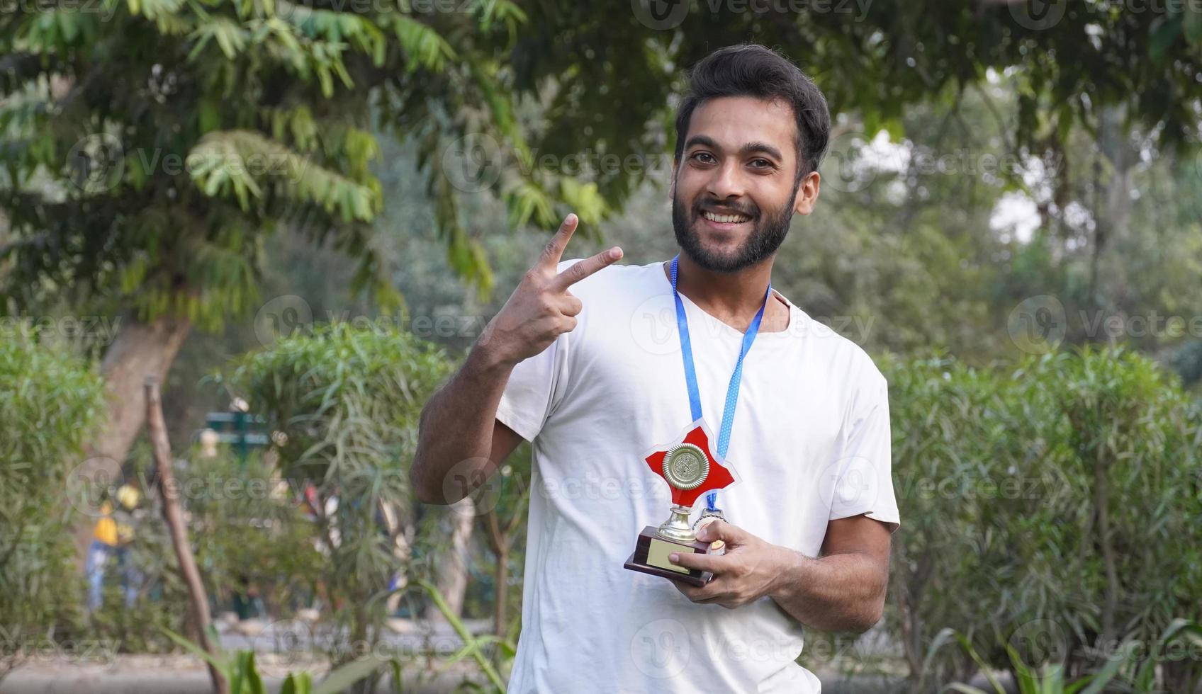 indian smart Collage, school boy holding gold medal and trophy cup photo