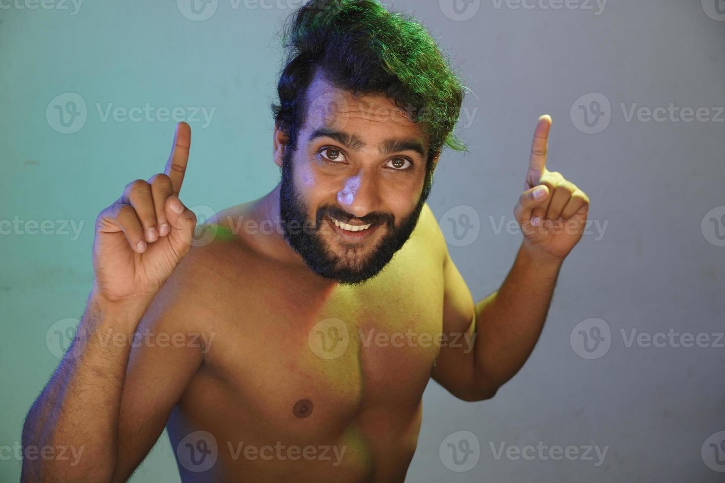 young man smiling face showing his hand for dancing without cloths studio shot photo