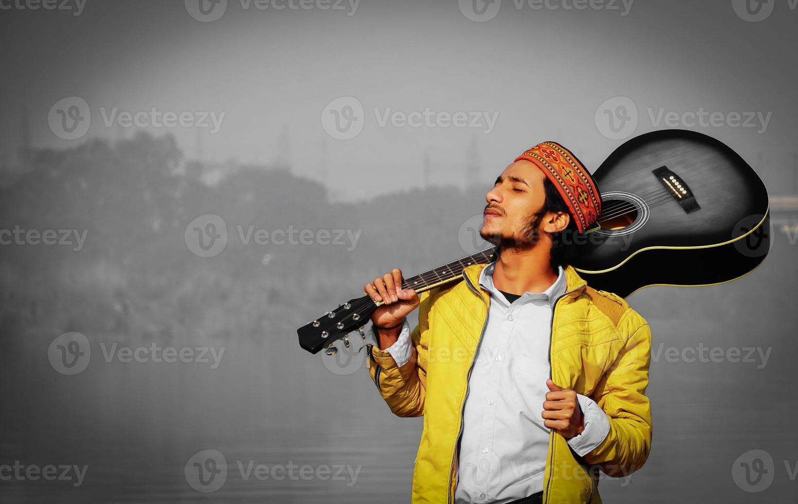 hombre dando pose con guitarra acústica en chaqueta amarilla foto