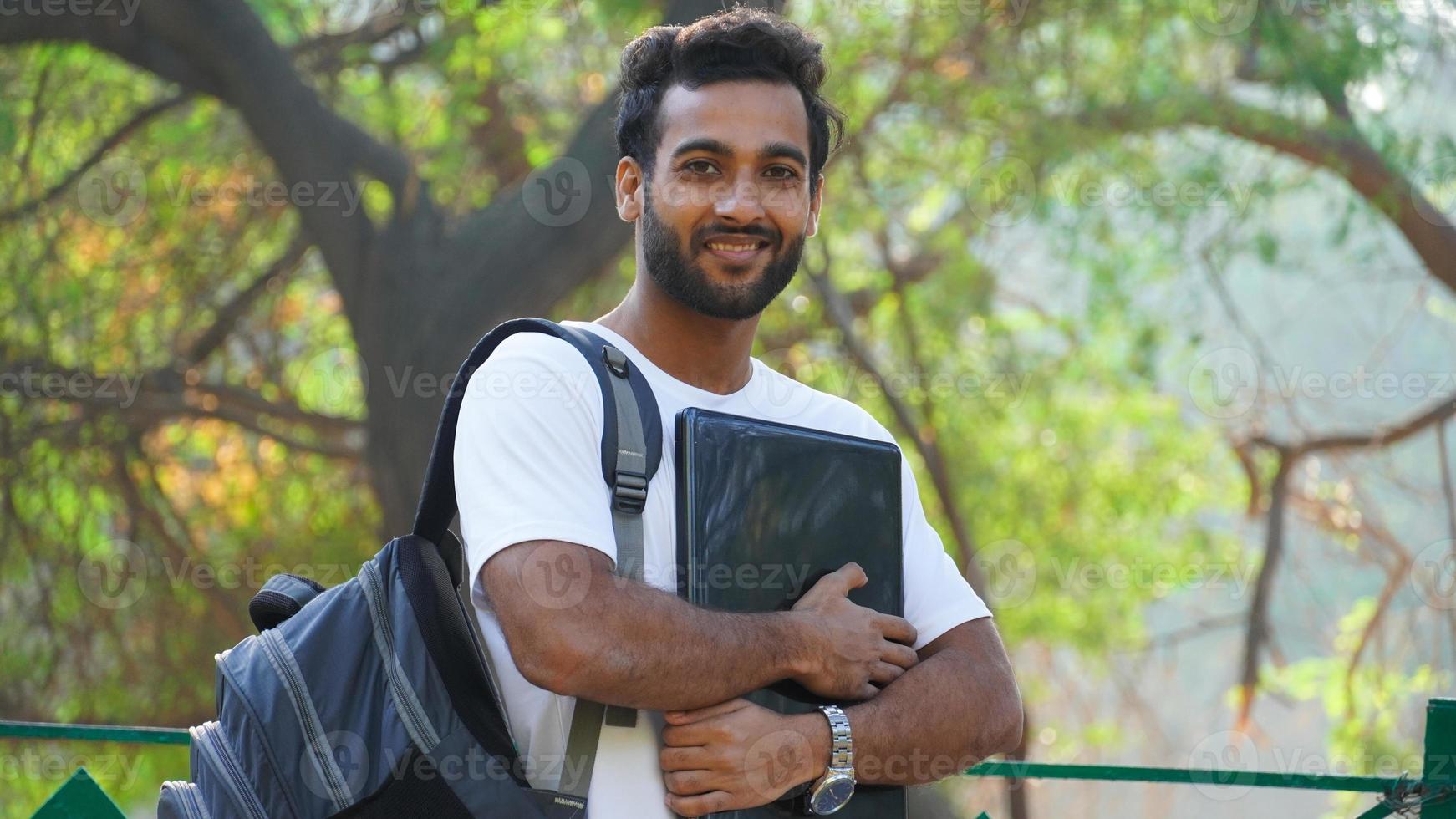 Cheerful Young student with laptop looking photo