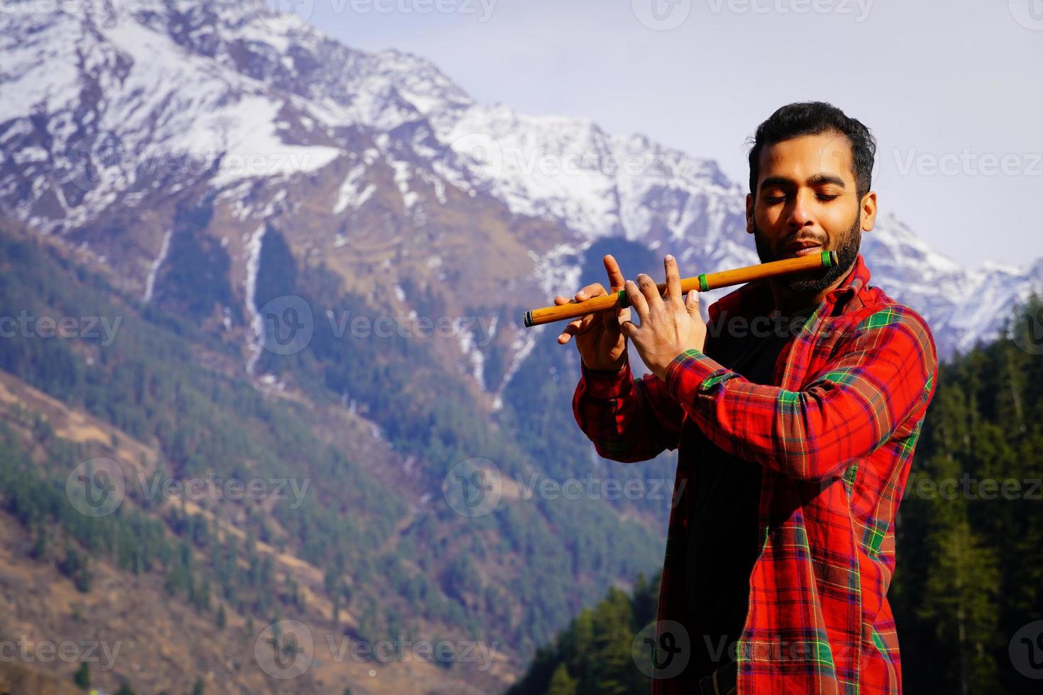 bansuri indian instrument Young boy playing bansuri Indian flute in mountains photo