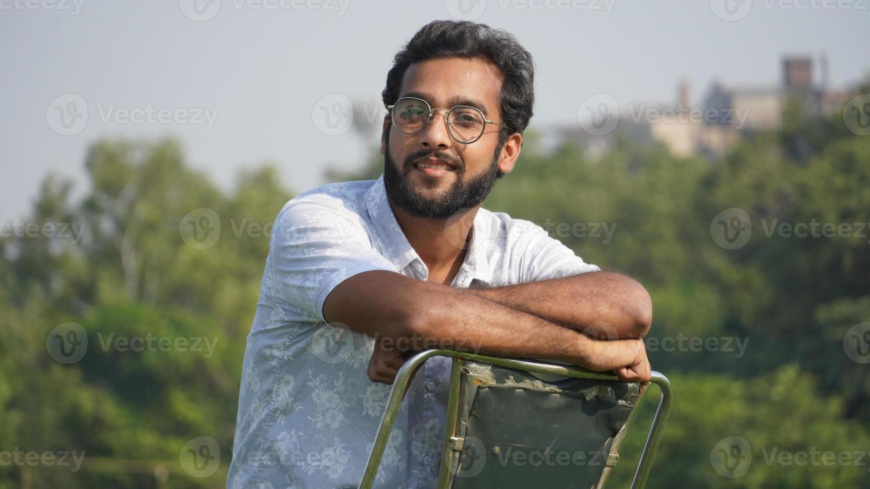 Portrait of man with sun glasses shitting on chair photo