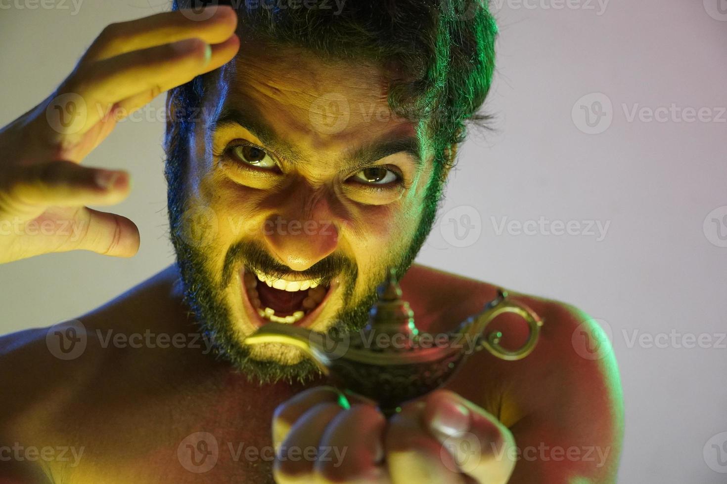 a young angry man with magical lamp and feeling angry like a king want to be powerful using the lamp photo